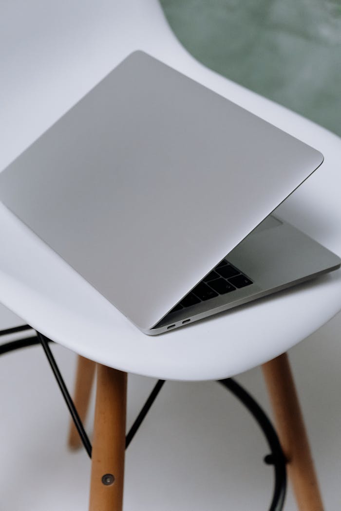 A sleek laptop rests on a modern Eames chair, showcasing minimalist design.